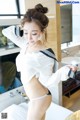 A woman in a white shirt and black panties posing in a bathroom.