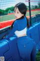 A woman in a blue and white outfit leaning against a fence.