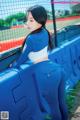 A woman in a blue and white outfit leaning against a fence.