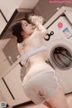 A woman standing in front of a washing machine in a kitchen.