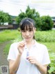 A woman in a white shirt holding a toothbrush in her hand.