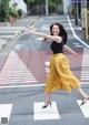 A woman in a yellow skirt is crossing the street.