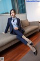 A woman in a business suit sitting on a couch.