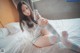 A woman sitting on a bed holding a can of soda.