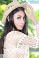 A woman wearing a straw hat is posing for a picture.