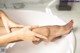 A woman's legs in a bathtub with her hands on her knees.