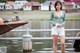 A woman standing on a dock next to a body of water.