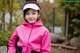 A young girl wearing a pink jacket and a white visor.