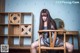 A woman sitting on a wooden chair in a room.