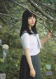 A woman in a school uniform standing in front of a tree.