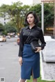 A woman in a black shirt and blue skirt posing for a picture.