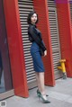 A woman in a black shirt and blue skirt posing for a picture.