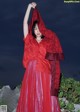 A woman in a red dress with a red shawl over her head.