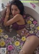 A woman laying in a bathtub filled with flowers.