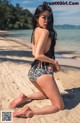 A woman in a bikini sitting on the beach.