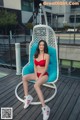 A woman in a red bikini sitting on a blue chair.