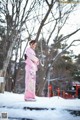 A woman in a pink kimono standing in the snow.