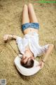 A woman laying on a hay bale wearing a white hat.