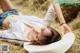 A woman laying on a pile of hay wearing a white hat.