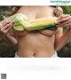 A woman holding a corn cob in front of her breasts.