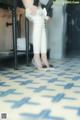 A woman in white pants and high heels standing on a tiled floor.