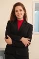 A woman in a black suit standing with her arms crossed.