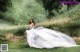 A woman in a white dress is standing in a field.