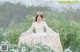 A woman in a white dress sitting in a field of flowers.