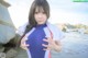 A young girl in a wetsuit standing on the beach.