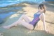 A woman in a bathing suit sitting on a rock by the ocean.