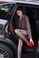 A woman sitting in the back of a car with her legs crossed.