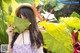 A woman in a straw hat holding a large leaf over her face.