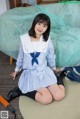 A woman in a school uniform sitting on the floor.