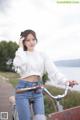 A woman sitting on top of a bike next to a lake.