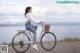 A woman riding a bike on a wooden dock by the water.