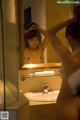 A naked woman standing in front of a mirror in a bathroom.