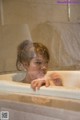 A woman in a bathtub looking out the window.