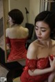 A woman in a red dress looking at herself in the mirror.