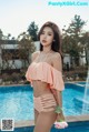 A woman in a pink bikini standing next to a pool.