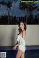 A woman in a white and black bathing suit standing next to a pool.