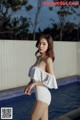 A woman in a white and black bathing suit standing by a pool.