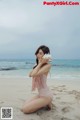 A woman in a pink bathing suit sitting on a beach.