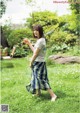 A woman walking in the grass holding a glass of orange juice.