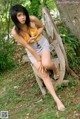 A woman sitting on a wooden bench in the woods.