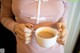 A woman holding a cup of tea with a spoon in it.