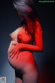 A pregnant woman with red paint on her body.