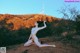 A naked woman sitting on a dirt road in front of a Hollywood sign.