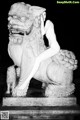 A naked woman sitting on top of a stone lion statue.