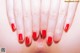 A woman's hand with a red manicure on her nails.