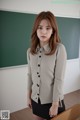 A woman standing in front of a blackboard in a classroom.